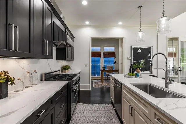 a kitchen with stainless steel appliances kitchen island granite countertop a stove a refrigerator a kitchen island a dining table and chairs with wooden floor