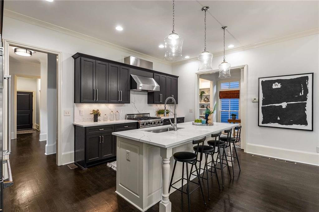 147 Hubbard Road Woodstock, GA 30188 - Photo 15 of 56 a kitchen with stainless steel appliances kitchen island granite countertop a stove a refrigerator a kitchen island a dining table and chairs with wooden floor