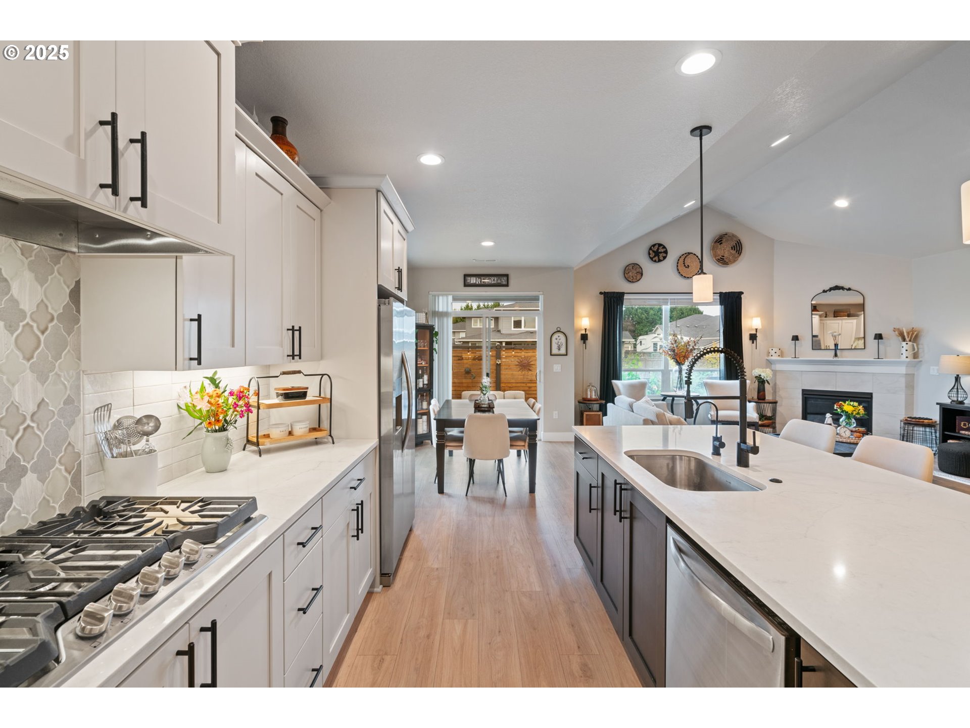 8842 North 3rd Circle Ridgefield, WA 98642 - Photo 24 of 46 a kitchen with kitchen island granite countertop a stove a sink a refrigerator and a dining table with wooden floor
