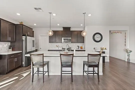 a kitchen with a dining table chairs cabinets and stainless steel appliances