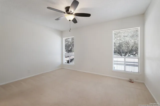 en empty room with windows and ceiling fan