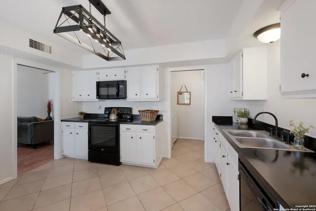 a kitchen with granite countertop a sink a stove top oven and cabinets