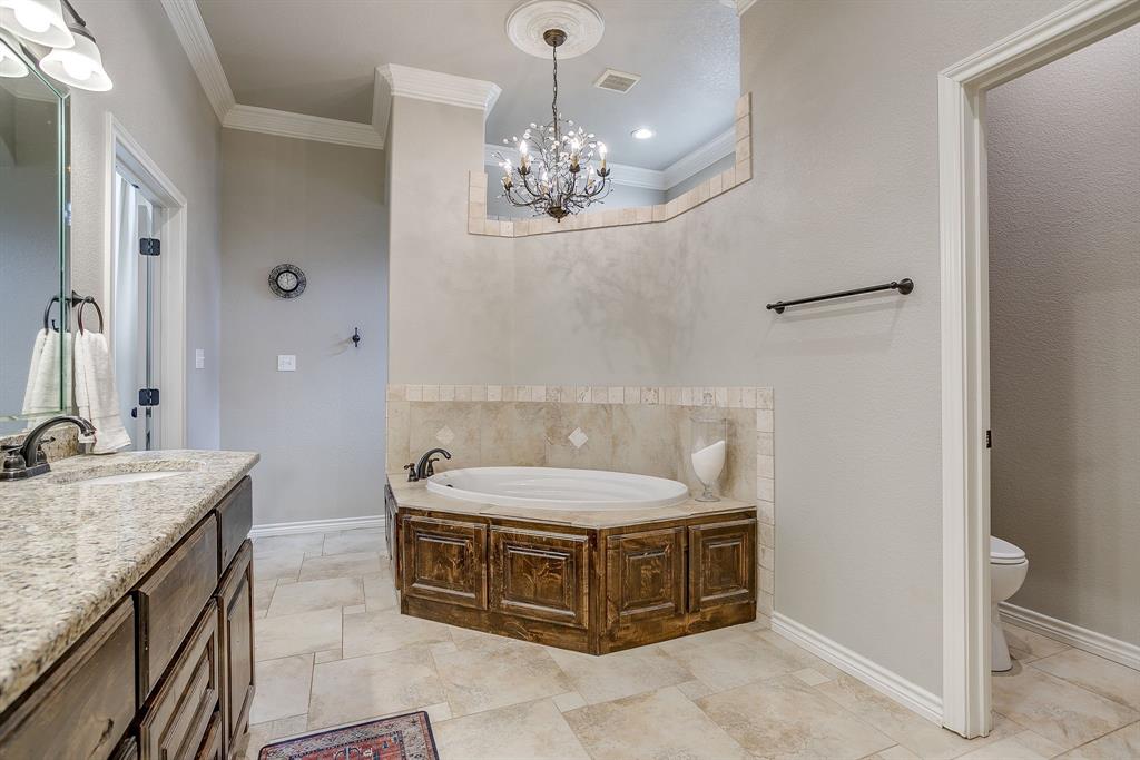1615 Sanger Drive Springtown, TX 76082 - Photo 20 of 40 a spacious bathroom with a granite countertop bathtub a sink and a mirror