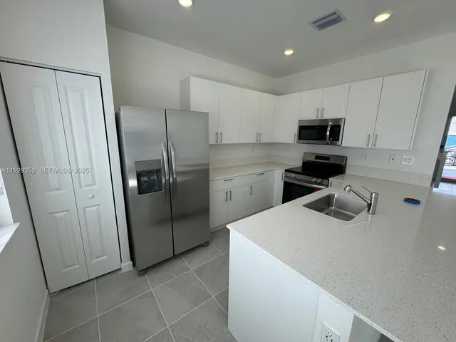 a kitchen with stainless steel appliances a refrigerator sink and microwave