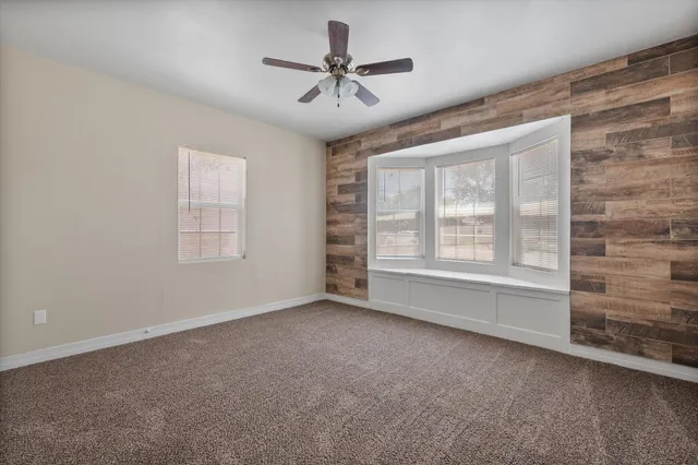 an empty room with windows and ceiling fan