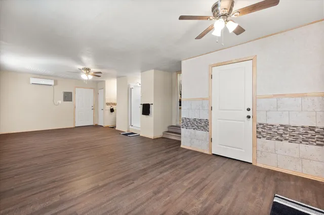 a view of an empty room with wooden floor and a ceiling fan