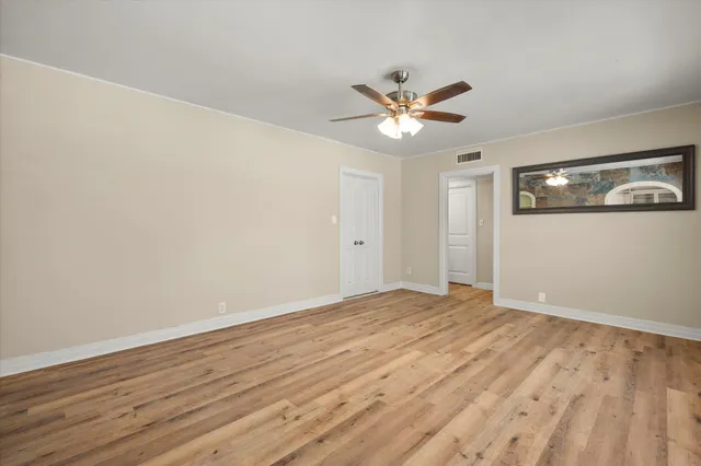a view of an empty room with window and wooden floor