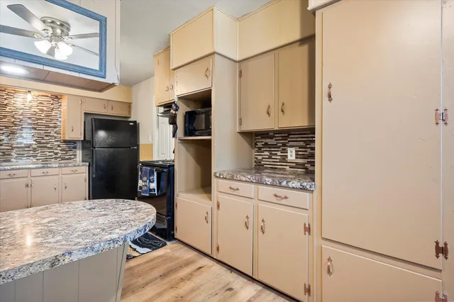 a kitchen with stainless steel appliances kitchen island granite countertop a refrigerator a stove and a sink with wooden floor