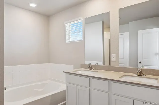 a bathroom with a tub sink and mirror