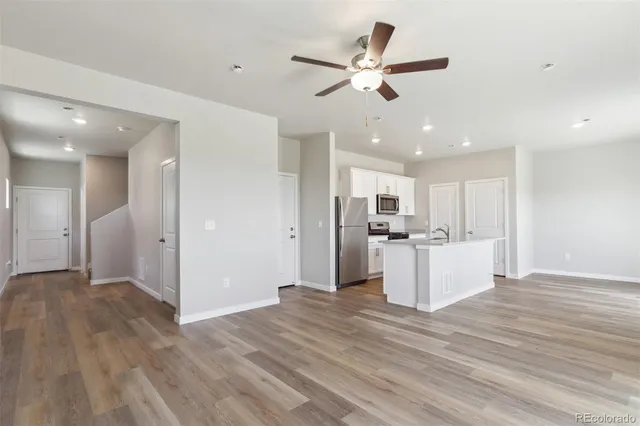 a view of a kitchen with wooden floor and a ceiling fan