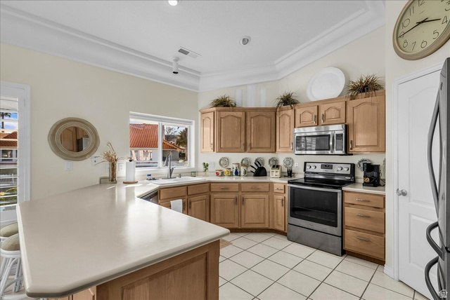 150 South Crystal Street, Unit 31 St. George, UT 84770 - Photo 12 of 20 Kitchen featuring stainless steel appliances, a kitchen breakfast bar, a peninsula, wood finish cabinets, and light countertops