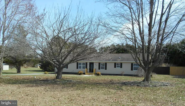 a front view of house with yard and trees in the background