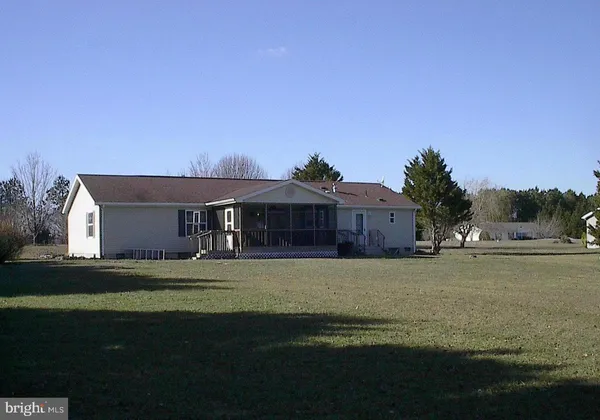 a front view of house with yard and trees in the background