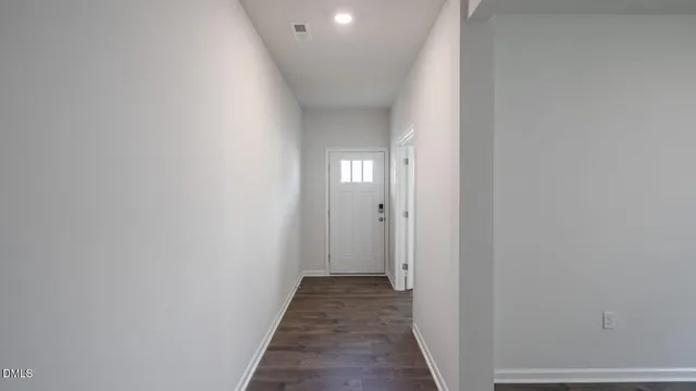 a view of an empty room with wooden floor and windows