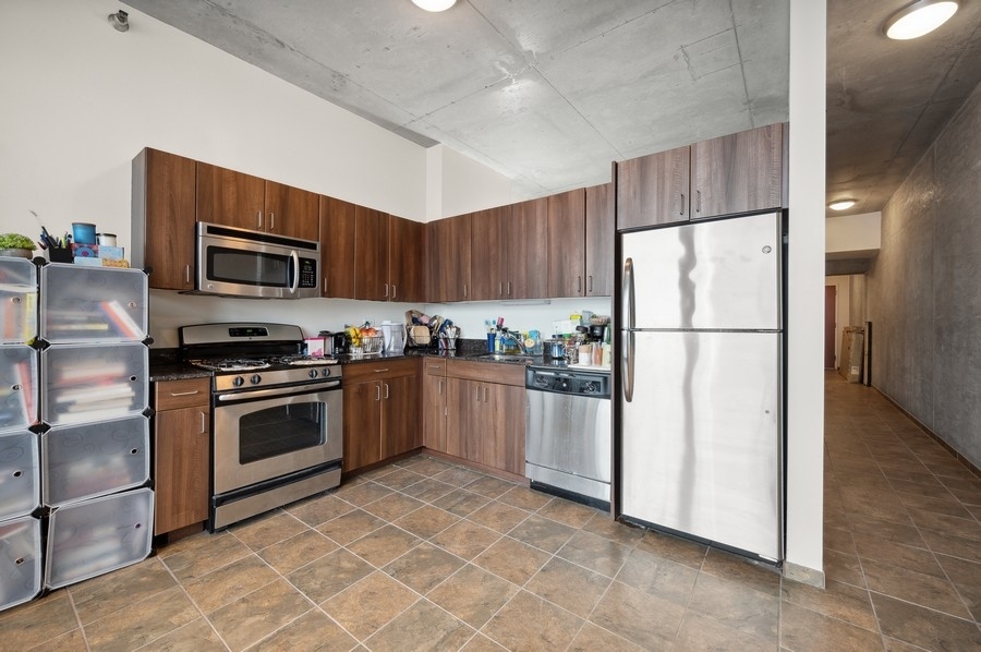235 West Van Buren Street, Unit 1506 Chicago, IL 60607 - Photo 5 of 16 a kitchen with granite countertop a refrigerator and a stove top oven