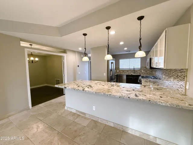 a large kitchen with kitchen island granite countertop a sink a counter and a refrigerator