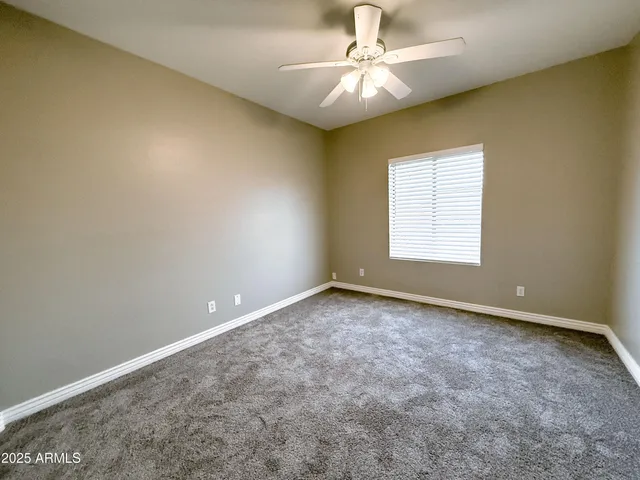 an empty room with a chandelier fan and windows