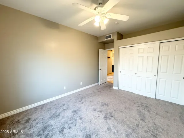 an empty room with a chandelier fan and closet area