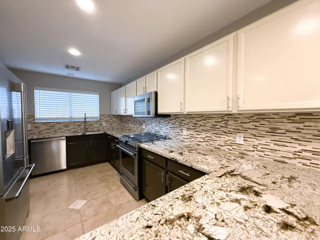 a kitchen with stainless steel appliances granite countertop a sink stove and cabinets