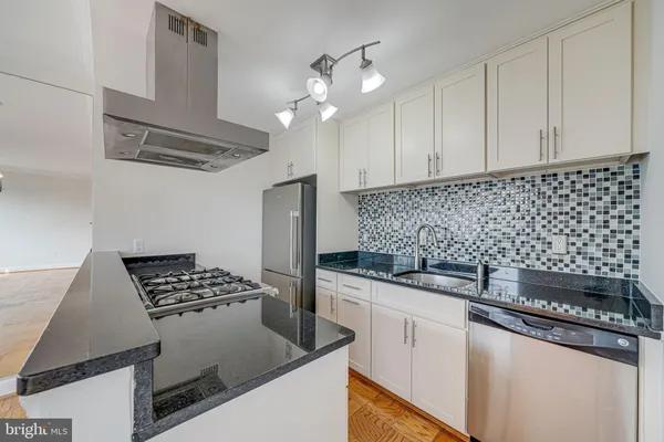 a kitchen with granite countertop a sink a stove and cabinets