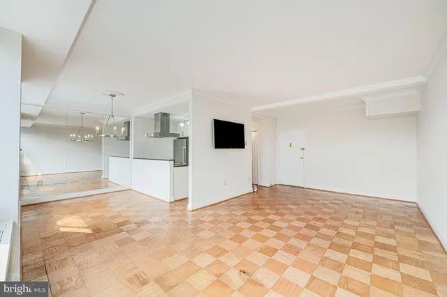 a view of a livingroom with wooden floor and kitchen view