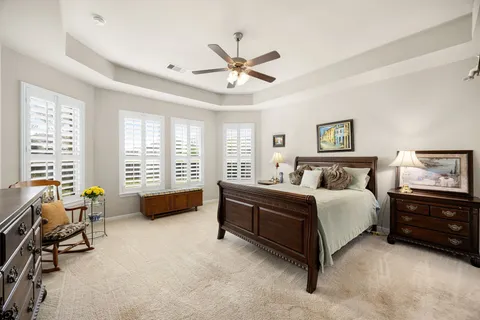 a spacious bedroom with a bed a couch and a ceiling fan