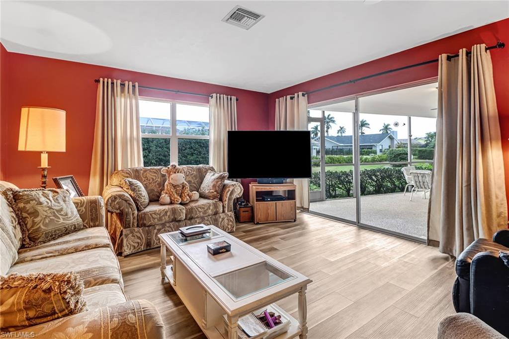 355 Valley Stream Circle Naples, FL 34113 - Photo 12 of 31 a living room with furniture a flat screen tv and a floor to ceiling window