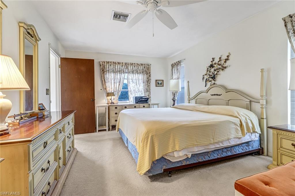 355 Valley Stream Circle Naples, FL 34113 - Photo 15 of 31 a bedroom with a bed and a chandelier