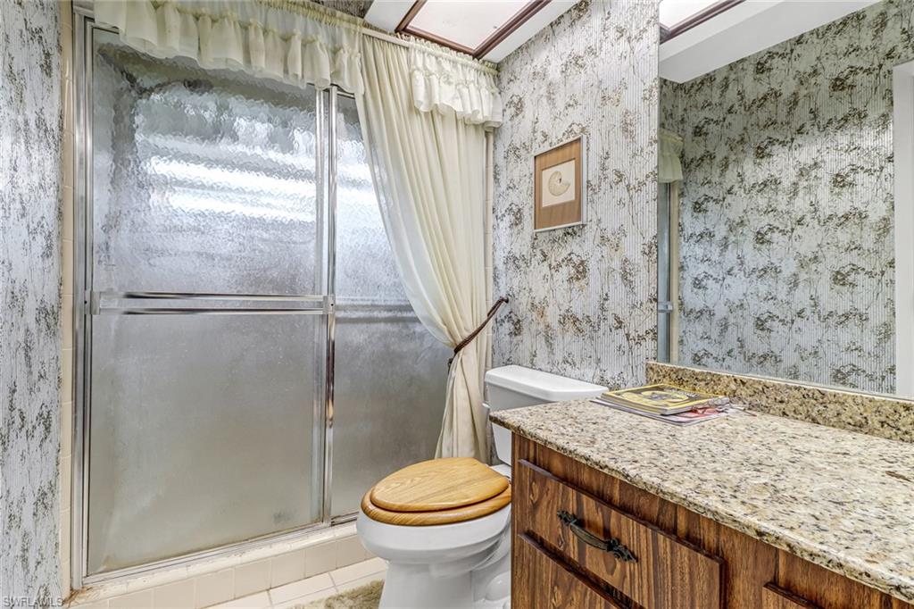 355 Valley Stream Circle Naples, FL 34113 - Photo 17 of 31 a bathroom with a granite countertop toilet a sink and a shower