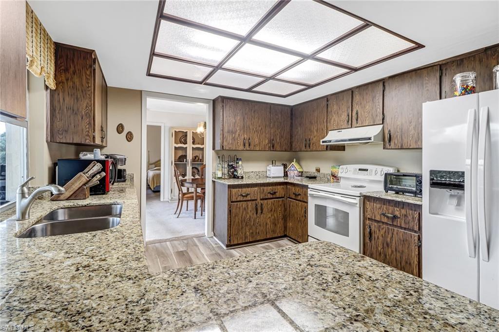 355 Valley Stream Circle Naples, FL 34113 - Photo 8 of 31 a kitchen with a refrigerator sink stove and cabinets