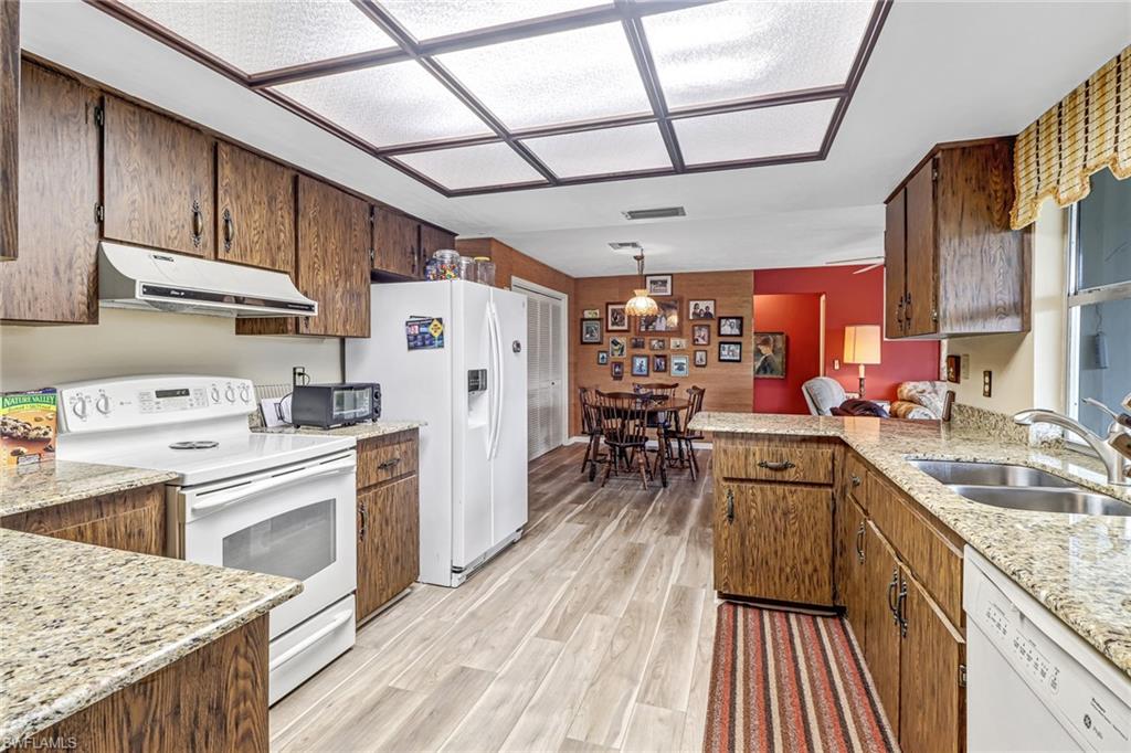 355 Valley Stream Circle Naples, FL 34113 - Photo 9 of 31 a kitchen with stainless steel appliances granite countertop a sink dishwasher stove refrigerator and cabinets with wooden floor