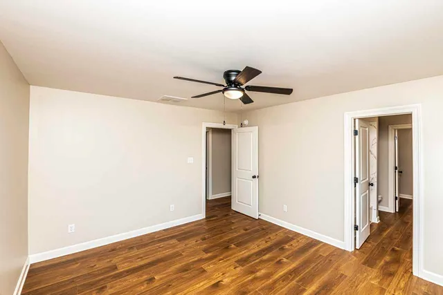a view of a room with wooden floor and a ceiling fan