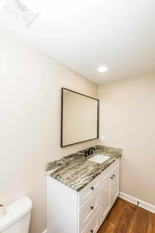 a bathroom with a granite countertop sink and a toilet