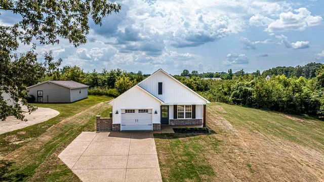 a front view of house with yard and trees in the background