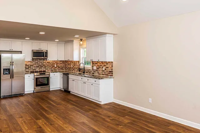 a kitchen with granite countertop white cabinets and white appliances