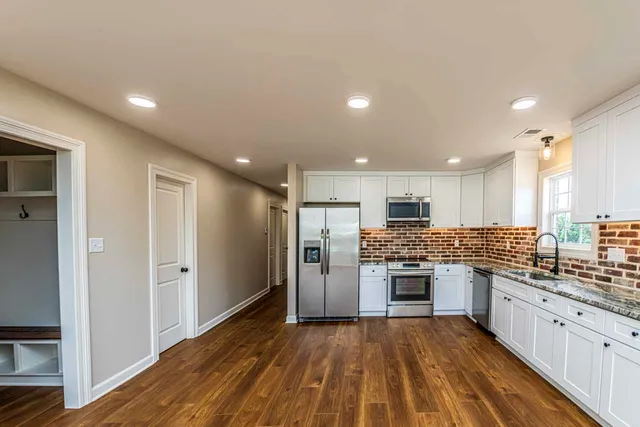 a kitchen with stainless steel appliances kitchen island granite countertop a refrigerator and a stove top oven