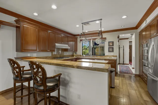 a kitchen with stainless steel appliances granite countertop table chairs and wooden cabinets