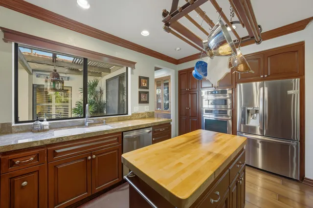 a kitchen with stainless steel appliances granite countertop a refrigerator a sink and a stove