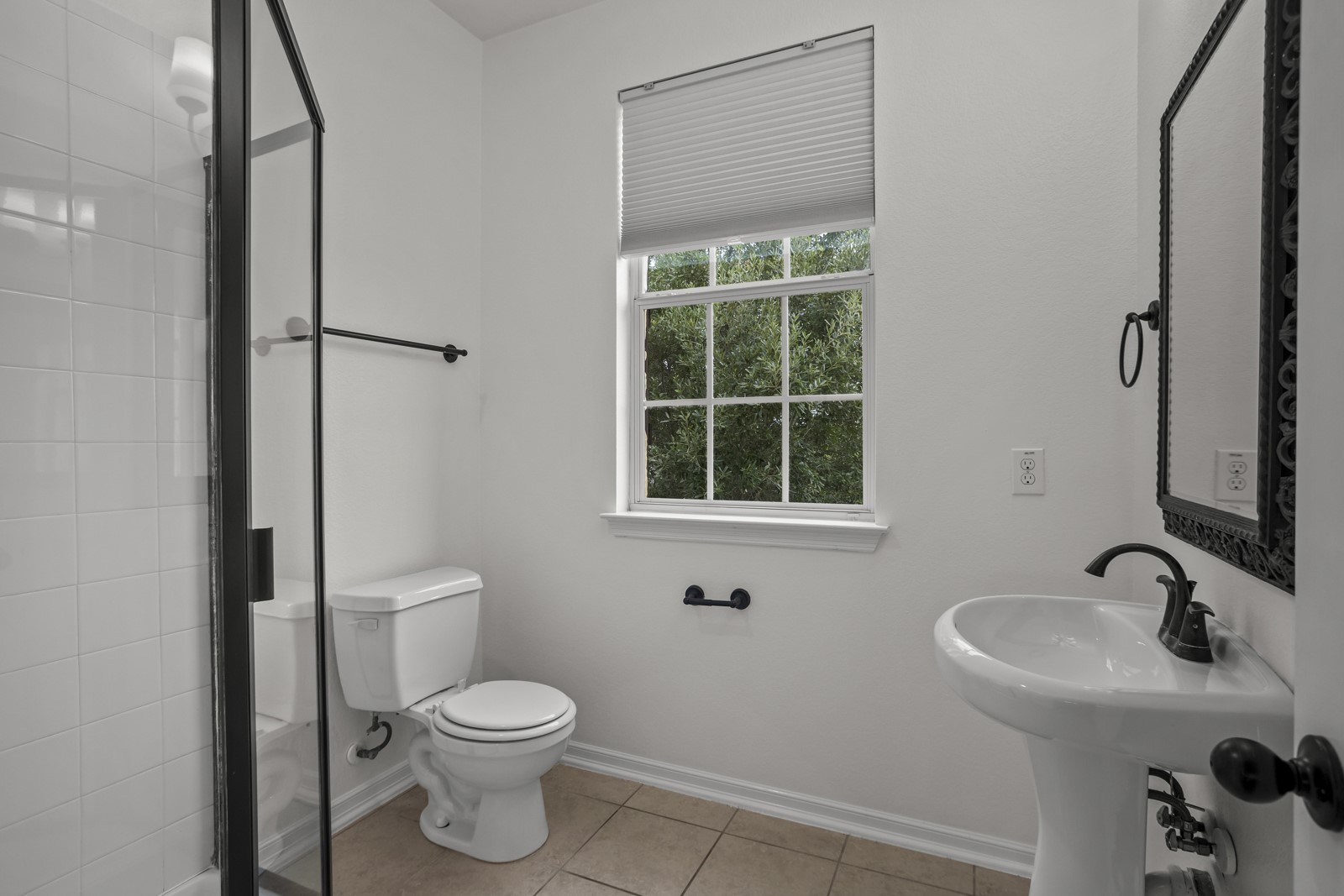 245 Razzmatazz Trail Buda, TX 78610 - Photo 26 of 37 Contemporary bathroom featuring a pedestal sink with a dark bronze faucet, a decorative framed mirror, and a window with privacy blinds