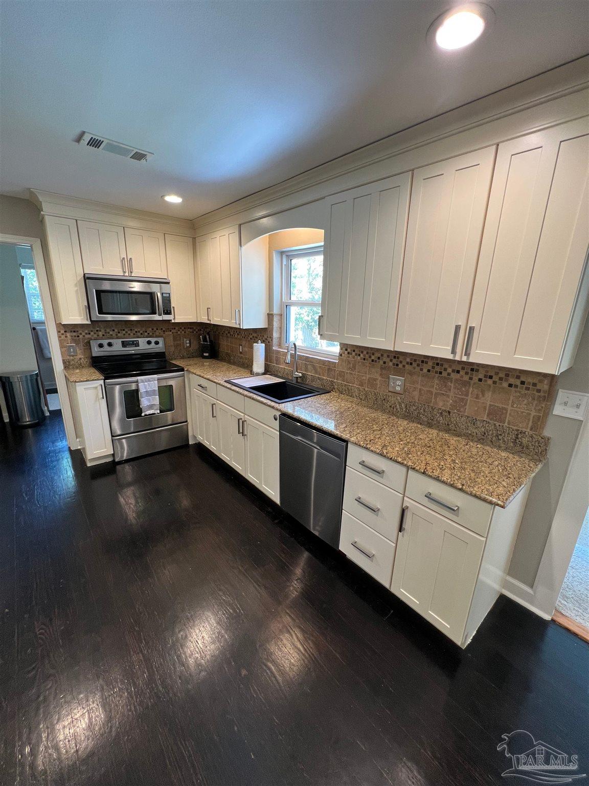 320 Gamarra Road Pensacola, FL 32503 - Photo 9 of 29 a kitchen with stainless steel appliances granite countertop a stove a sink dishwasher and a microwave oven with wooden floor