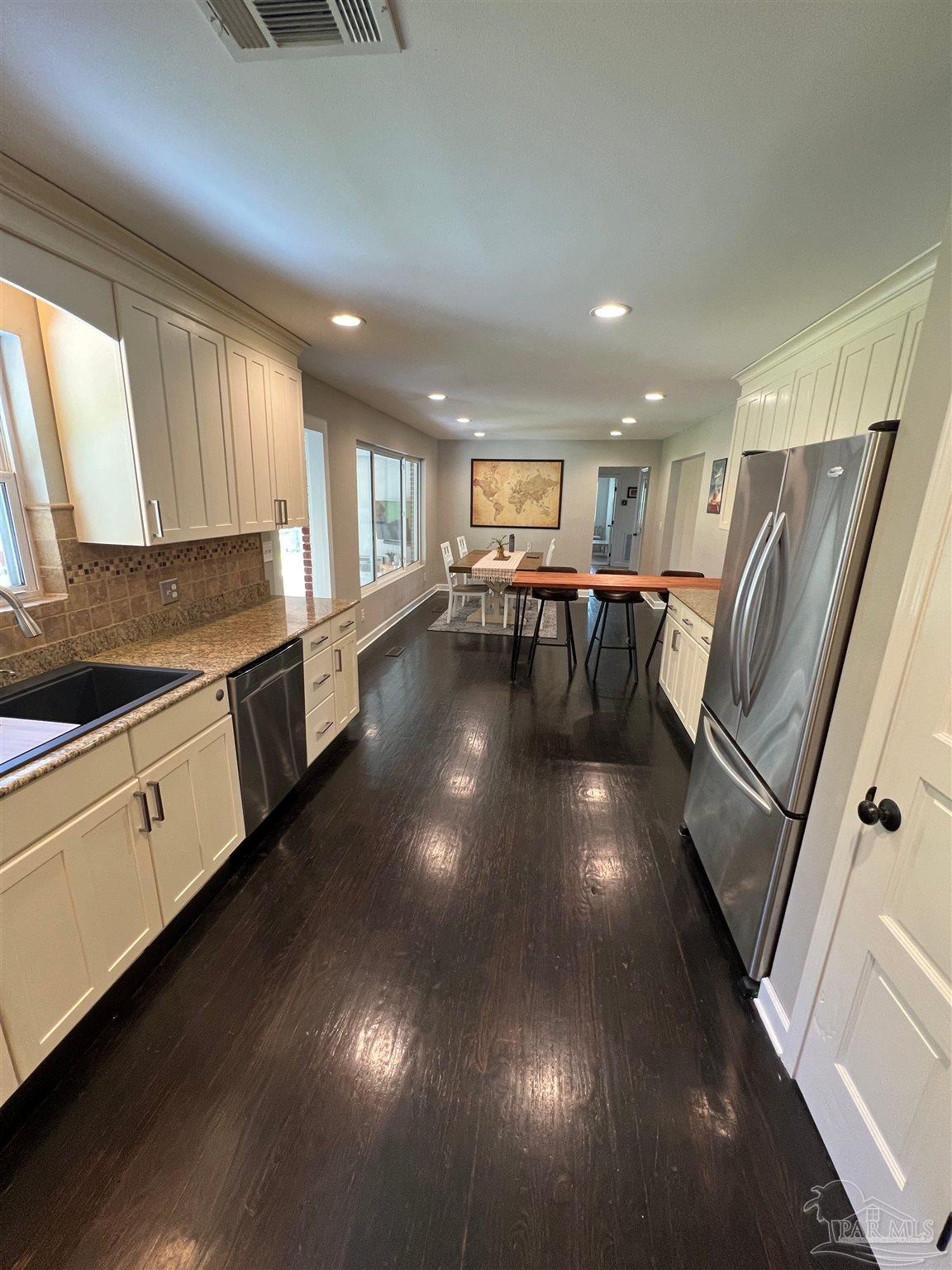 320 Gamarra Road Pensacola, FL 32503 - Photo 10 of 29 a kitchen with stainless steel appliances granite countertop a refrigerator a sink dishwasher a stove and a dining table with wooden floor