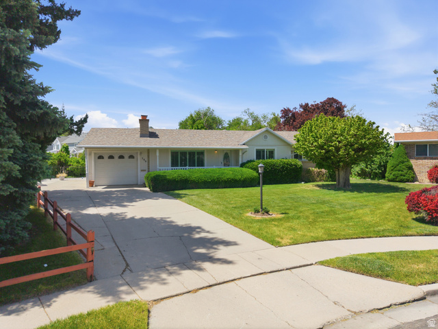 148 Tennyson Avenue Sandy, UT 84070 - Photo 48 of 55 Ranch-style residence featuring a single-car garage with arched window accents, a prominent front lawn with mature trees and shrubbery, and a concrete driveway leading to the street