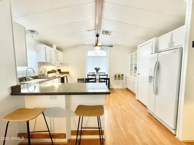 a kitchen with stainless steel appliances granite countertop a refrigerator a stove and white cabinets with wooden floor