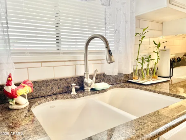 a kitchen with stainless steel appliances granite countertop a stove top oven a sink a dining table and chairs with wooden floor