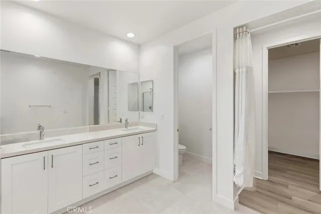 a bathroom with a double vanity sink a mirror and a toilet