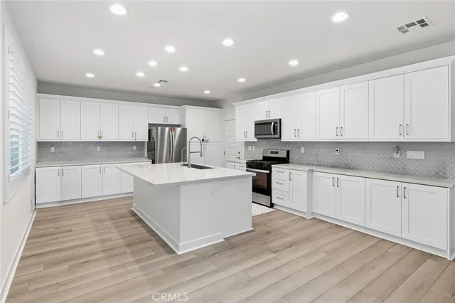 a large kitchen with stainless steel appliances granite countertop a stove a sink and white cabinets