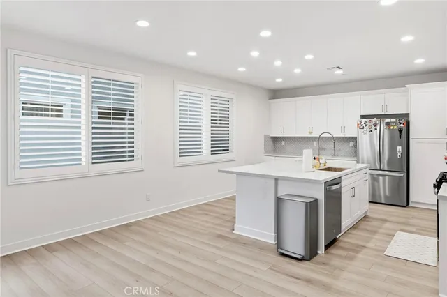 a large kitchen with kitchen island a sink wooden floor and stainless steel appliances