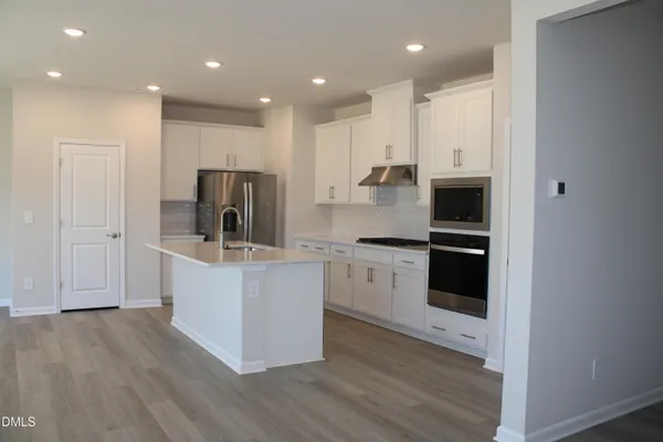 a kitchen with kitchen island stainless steel appliances sink refrigerator and microwave