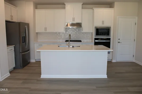 a view of a kitchen with stainless steel appliances wooden floor and cabinets