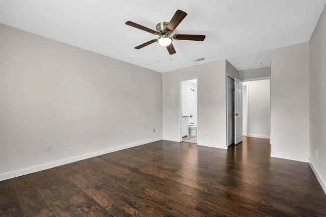 an empty room with wooden floor and ceiling fan